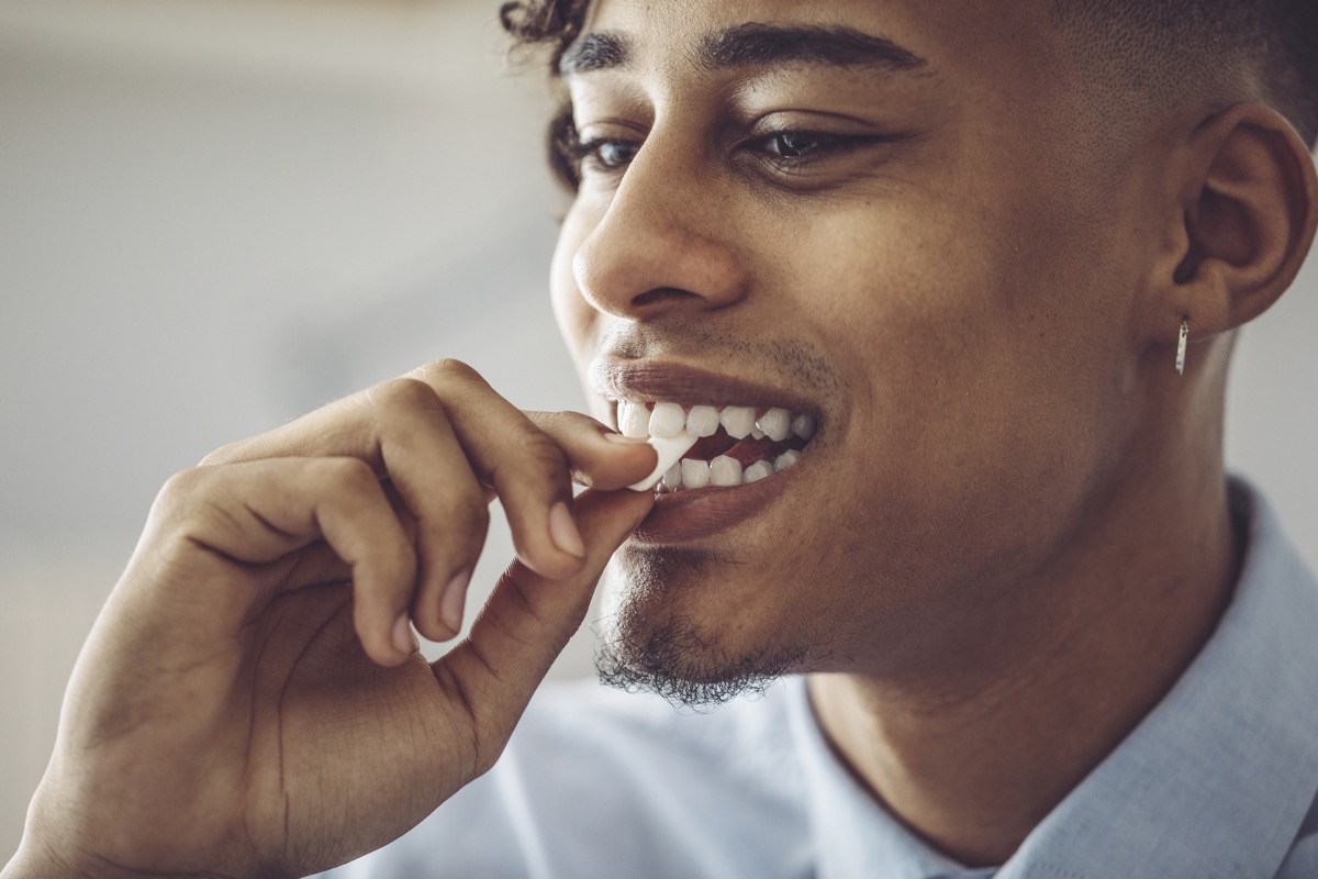 man putting chewing gum in his mouth