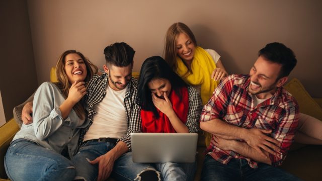 Friends looking at laptop and laughing