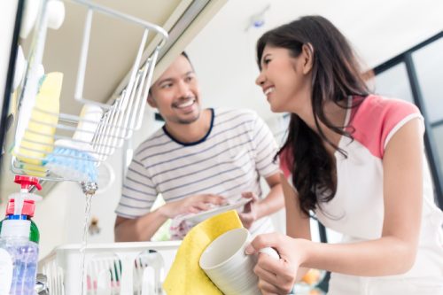 young woman and man taking dishes out of dishwasher