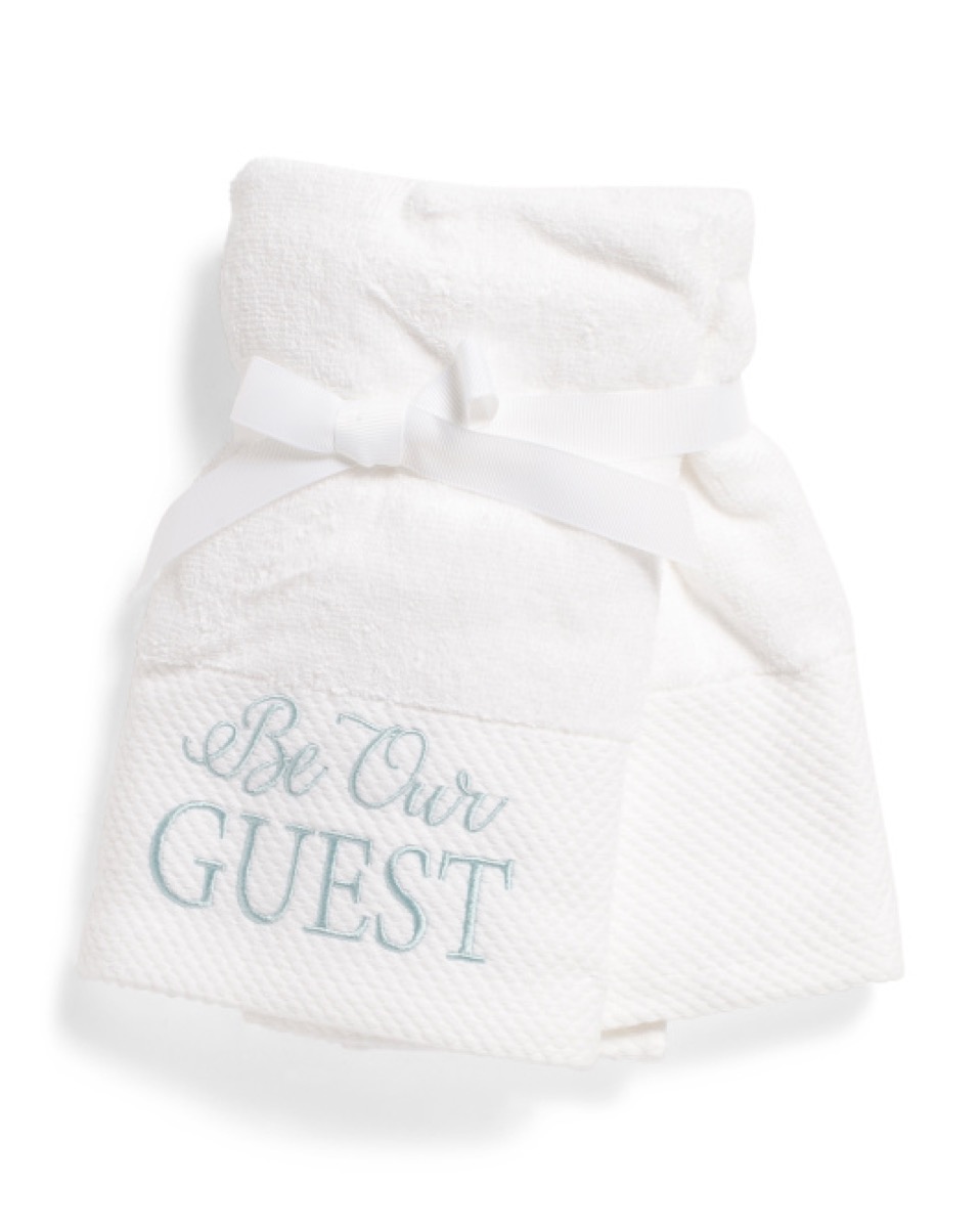 white hand towel with "be our guest" written on it, bathroom accessories