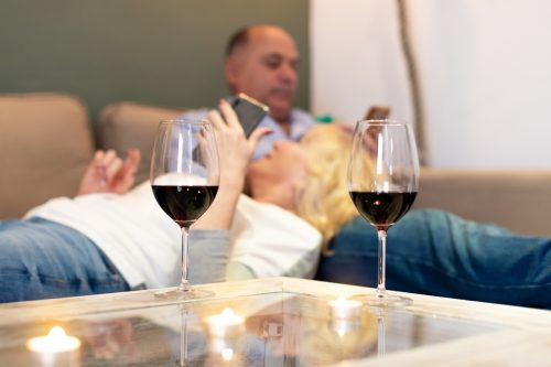 Senior couple on couch with wine and cell phones