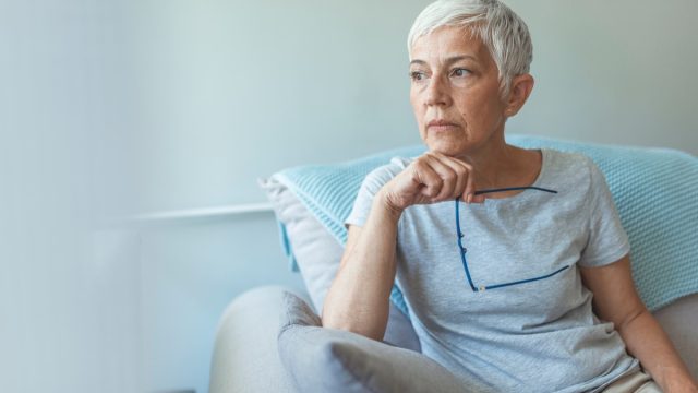 older woman sitting on the couch looking worried