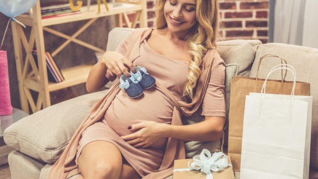 pregnant woman holding baby booties over stomach, pregnant gifts