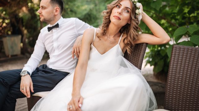 Newlywed bride and groom sitting on a sofa angry at each other in a middle of an argument.