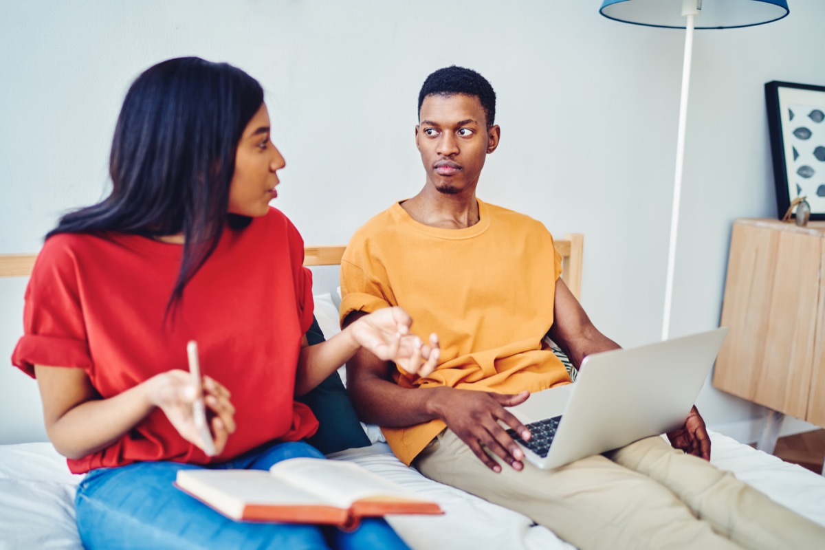 a couple sitting on their bed with one partner being too negative