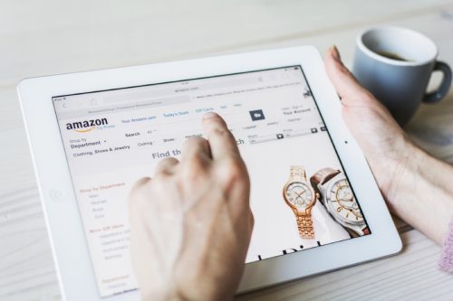 woman's hand clicks on tablet screen while shopping on amazon for watches