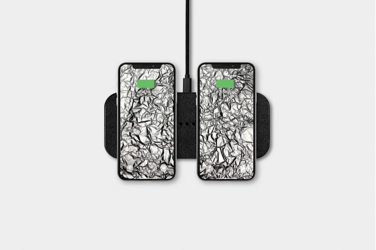 courant dual device leather charger with two phones on it