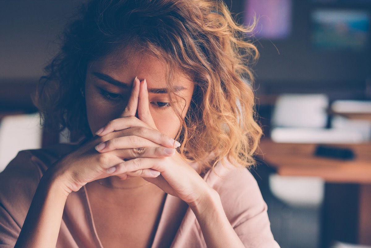young Asian woman looking worried with hands over face