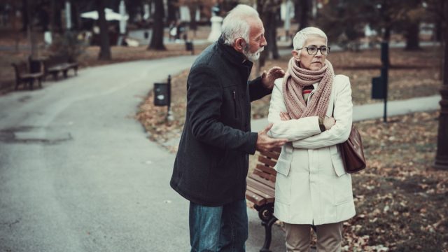 Elderly Couple in Warm Clothing Arguing in a Park During Cold Autumn Day.