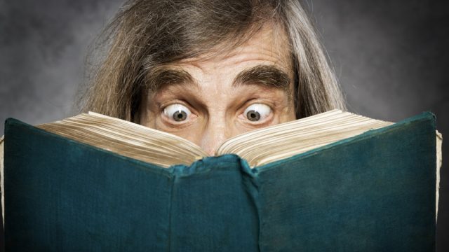 senior man looks shocked reading book