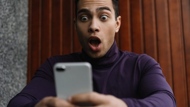 man of color looks shocked at phone