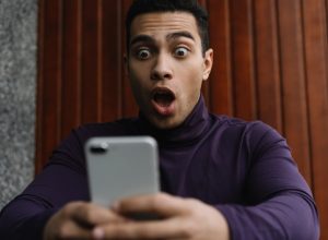 man of color looks shocked at phone