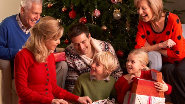 white grandparents, mother, father, and young daughter opening gifts
