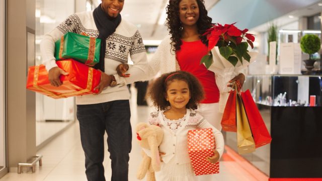 30-something black mother and father and young daughter shopping for holiday gifts at a department store or mall