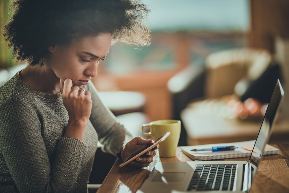confused woman looking at her phone with a worried face