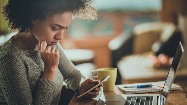 confused woman looking at her phone with a worried face