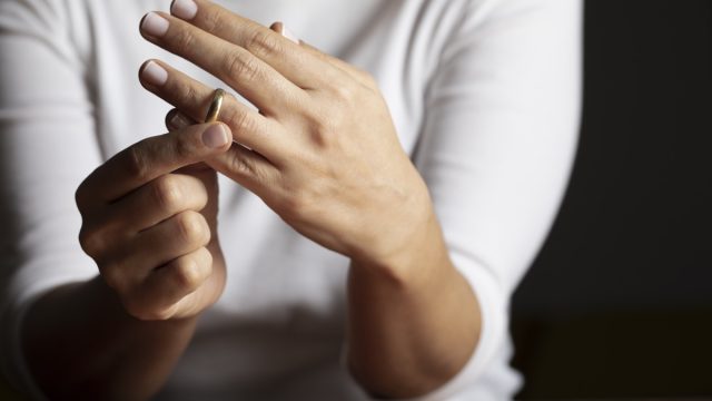 hands of white woman who is about to taking off her wedding ring.
