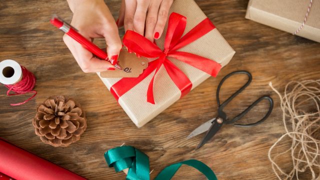 white woman filling out gift tag on christmas present