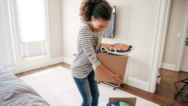 young black woman packing up boxes inside home