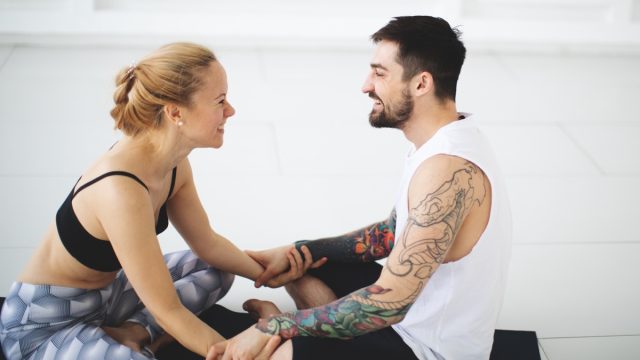 Young woman and man talking after yoga classes while smiling