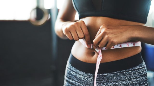 close up of woman measuring her waist at the gym