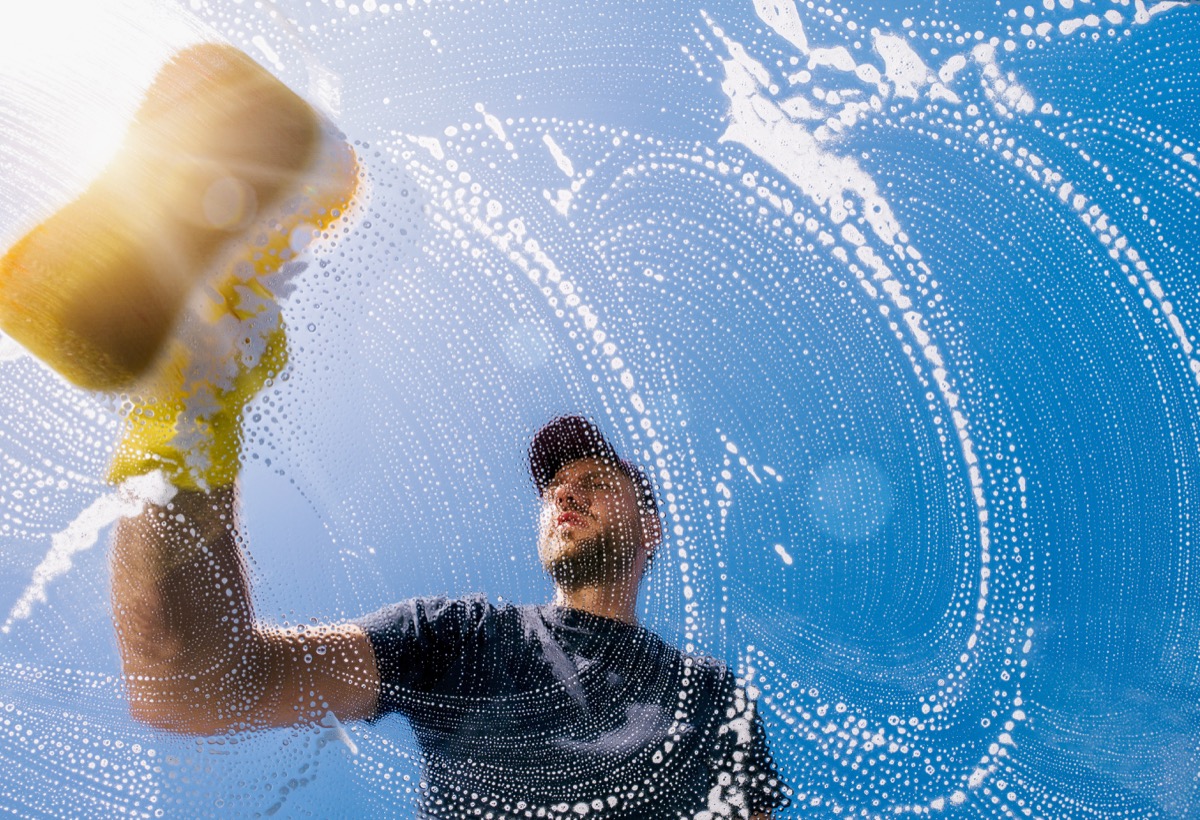 man cleaning window with sponge