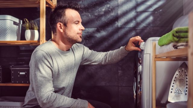 man looking at washing machine setting the presets