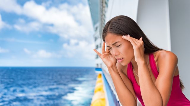 woman leans over cruise ship balcony seasick