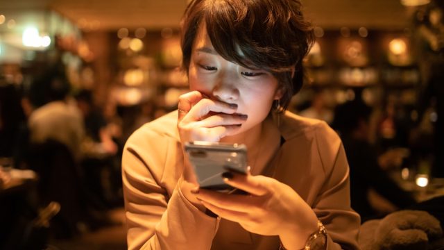 young woman using smart phone in cafe after work