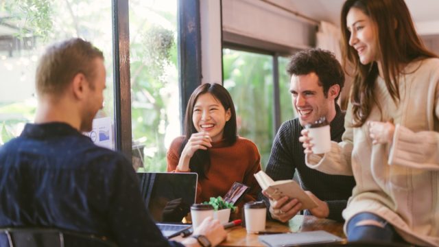 Group of friends chatting and using laptop in cafe at the coffee shop