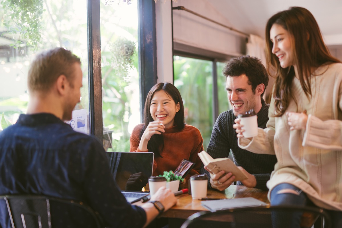 Group of friends chatting and using laptop in cafe at the coffee shop