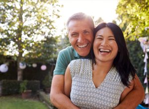 happy middle aged asian woman and white man outdoors