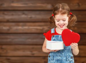 little girl with pigtails opening heart shaped box