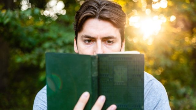 man reads in amazement at an old book about adventures, imagination and literature.