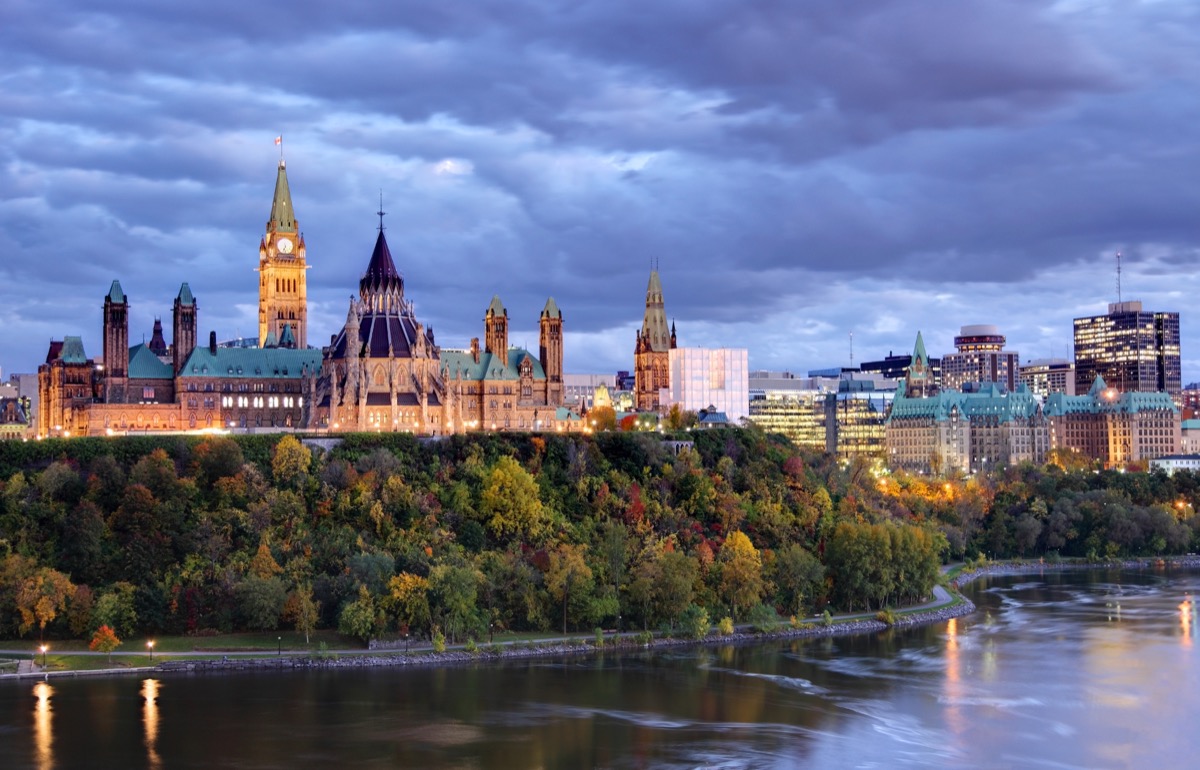 parliament Hill atop a dramatic hill overlooking the Ottawa River in Ottawa, Ontario in autumn. Parliament Hill is home to Canada's federal government and is the centrepiece of Ottawa’s downtown landscape. Ottawa is known for is high-tech business sector, vast array of museums and high standard of living.
