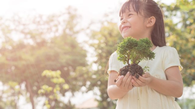little girl holding plant oudoors