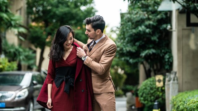 man helping woman put on her coat in the middle of the road