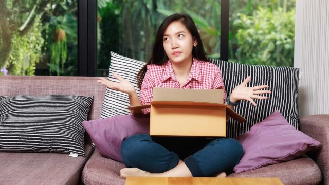 upset young asian woman opening box