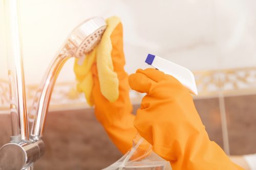gloved hands cleaning shower head
