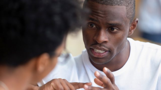 black man having a serious conversation with a woman, whose head is to the camera