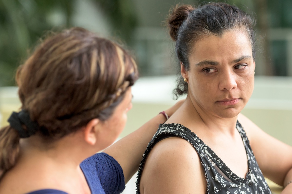 Sad latinx woman being comforted by a friend or sister