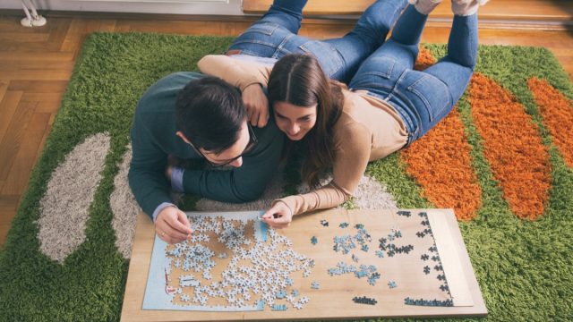 young white couple doing jigsaw puzzle on floor
