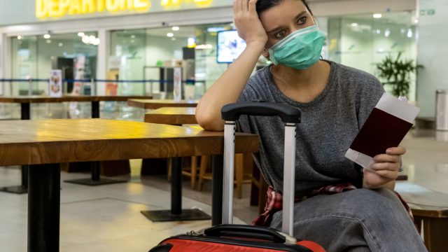 A female traveler sitting with her luggage looking distressed