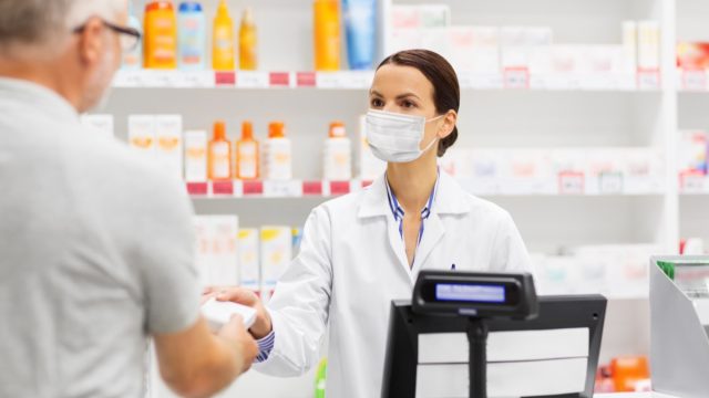 Man buying something from pharmacist with mask on