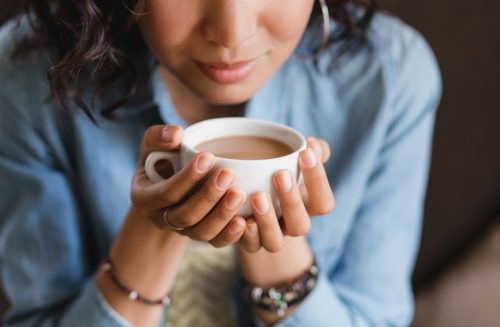 Woman trying to smell a cup of coffee