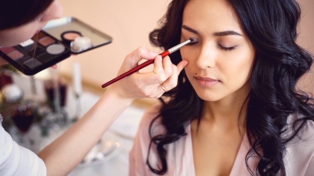 Makeup artist applying eyeshadow on woman
