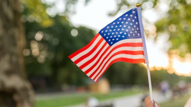 american flag held by white hand