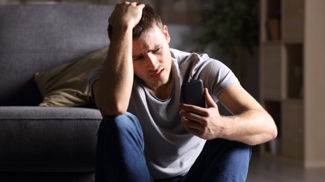 sad man looking at phone and holding his hand
