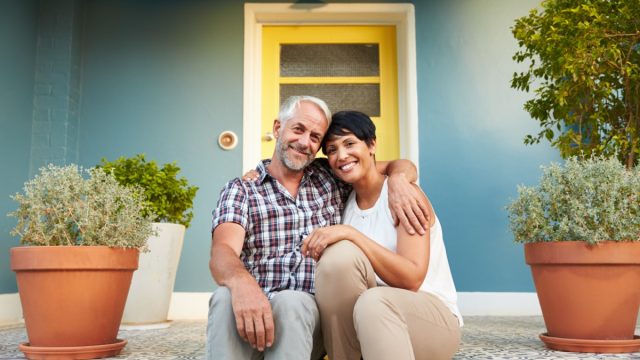 attractive middle-aged interracial couple sitting on the front stoop or porch of their home