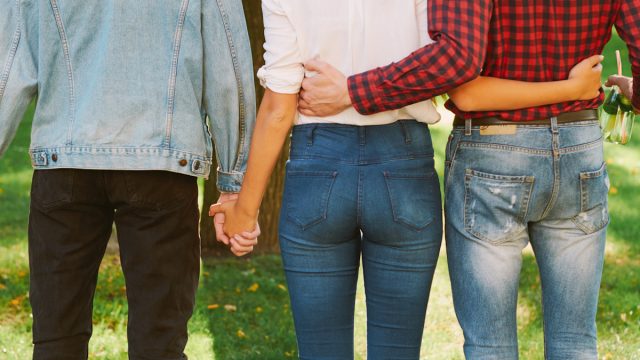 Woman standing with two guys in nature park.